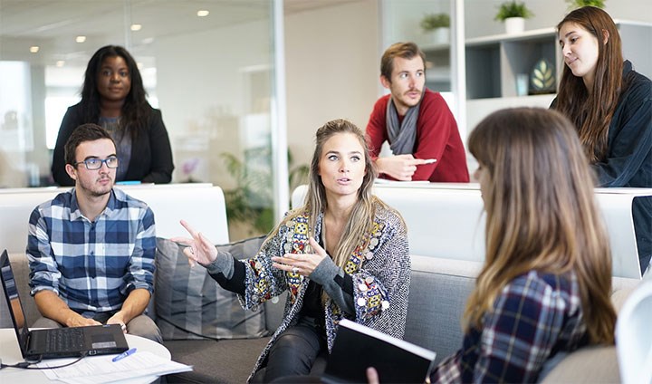 People in a meeting, sitting and talking with each other.