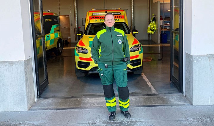 Cecilia Sixtensson i ambulanskläder framför en ambulans.