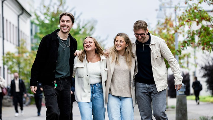 Fyra studentambassadörer som går på campus. 