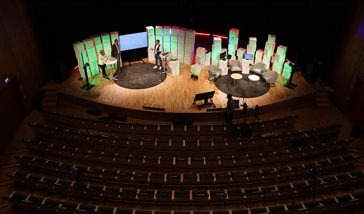 Musikhögskolans scen fotograferad uppifrån. Framför scenen (där det finns stolar och kulisser) står kameror. Salongen är helt tom.