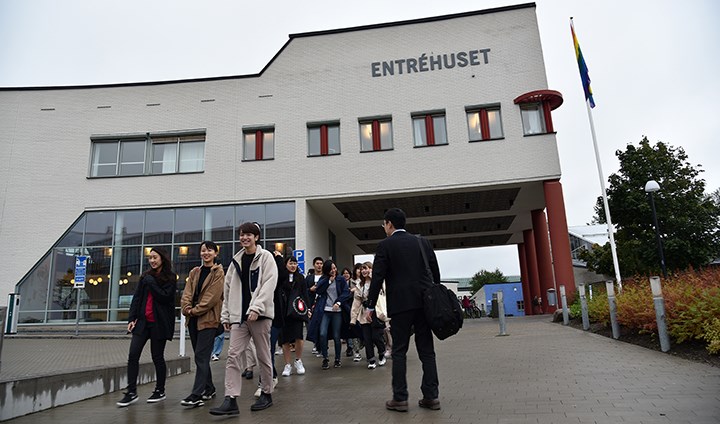 Students and teaching staff from Yokohama walking in front of a white building that has the sign “Entréhuset”. Students are laughing and enjoying themselves.