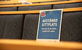 Skylt med texten "Avstängd sittplats" på stolar i en aula.