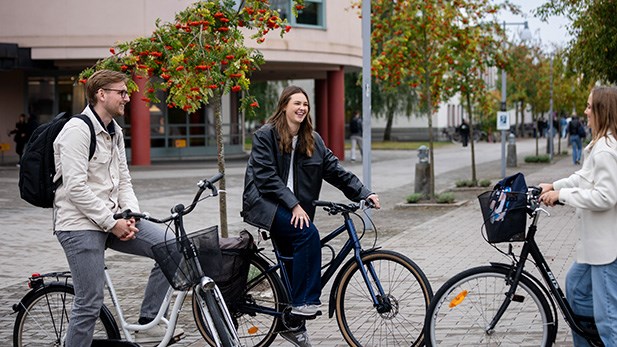 Tre studenter med sina cyklar på campus.