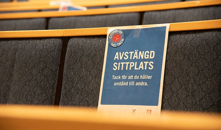En skylt med texten "Avstängd sittplats" fäst på en rad med stolar i en hörsal.