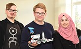 Andreas Persson, Max Niia och Ateka Al-Nuaimi i en föreläsningssal med roboten i lego.