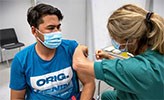 En ung man får vaccination av en sjuksköterska.