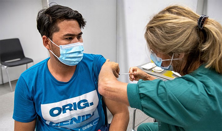 En ung man får vaccination av en sjuksköterska.
