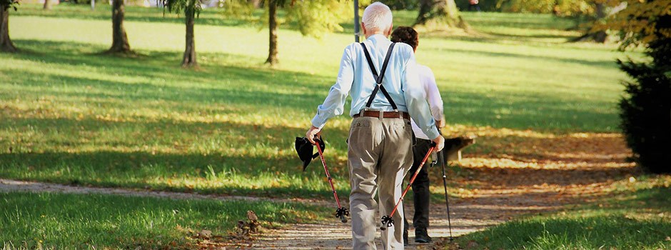 Two older people walking in the park. 