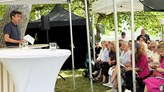 Andreas Bergh vid ett vitt podie framför publik i Almedalen. 