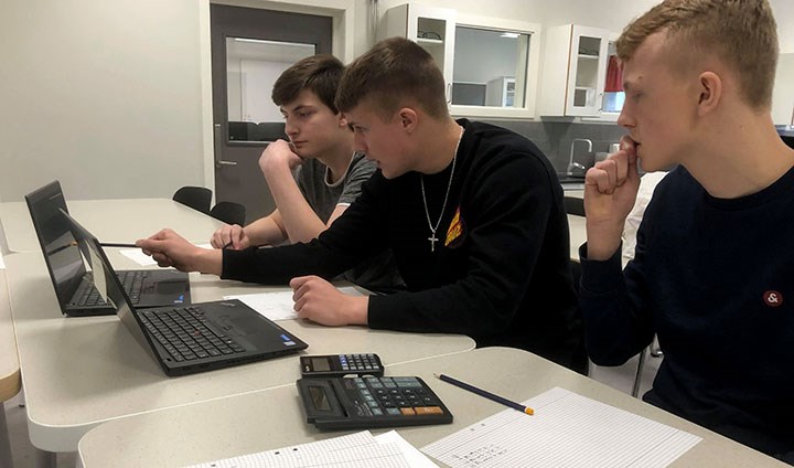 Tre elever sitter framför datorer och tävlar.