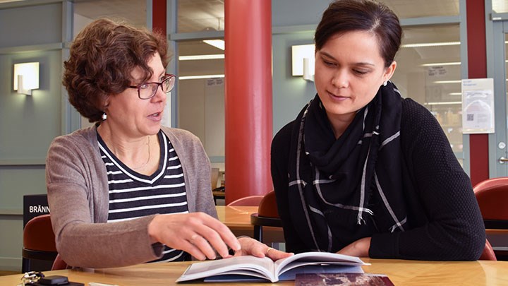 Photo of two people reading and pointing in a book.