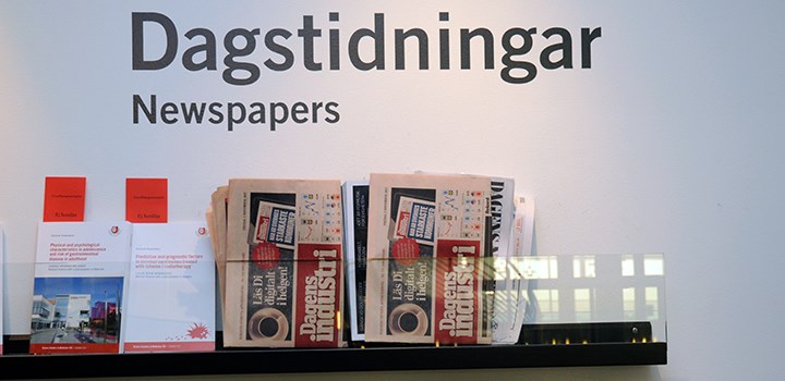 Två dagstidningar på en hylla under skylt med texten "Dagstidningar"