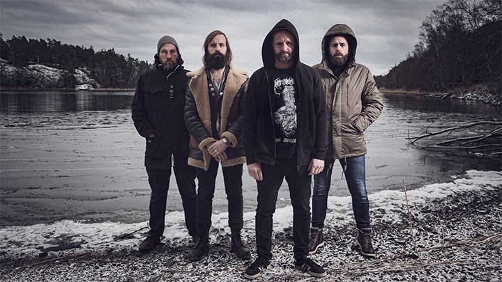 Horndal’s four metal band members standing on the shore of a lake.