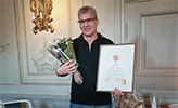 Anders Lindén med ett diplom och blommor.