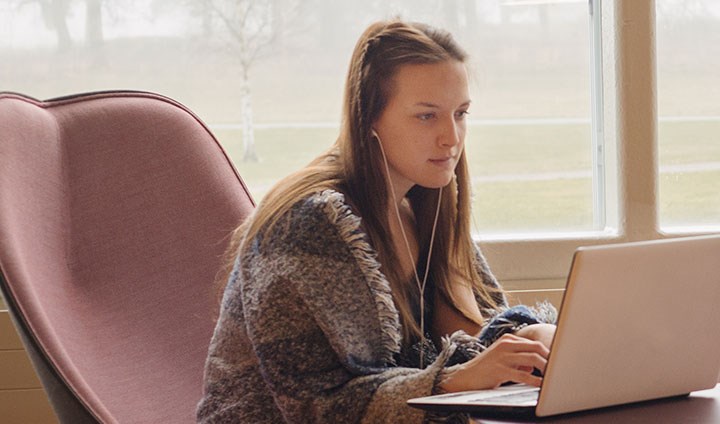 Kvinnlig student sitter vid ett bord med en dator. 