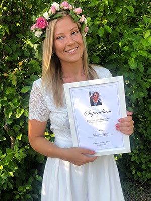 Linnea med blomsterkrans ihåret och stipendium i handen.