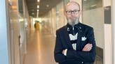 Magnus Lodefalk standing with crossed arms and with a long hallway behind him