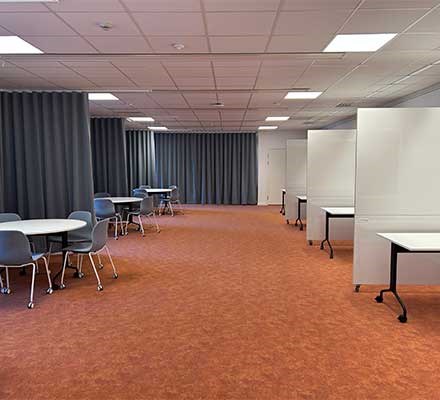 Vy 2 runda bord i grupp vid draperier och bord i grupputrymmen skapade av whiteboardväggar