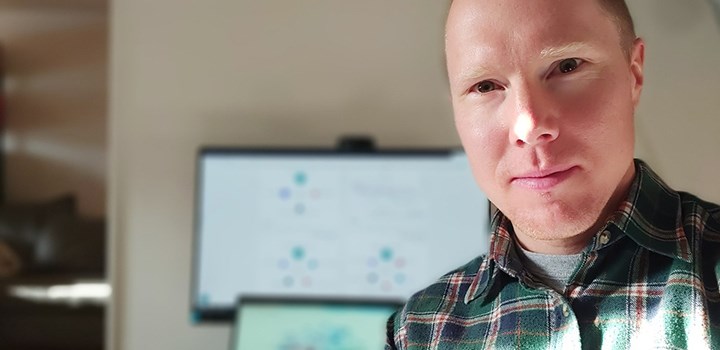 Foto på Johan Fredriksson ståendes framför en datorskärm.