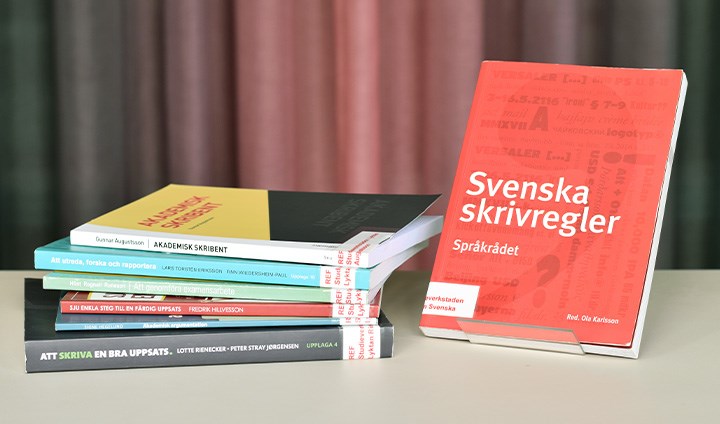 Foto på sju språk- och skrivhandböcker som ligger och står på ett bord.