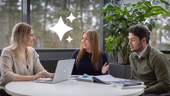 Några studenter med datorer samlade runt ett bord.