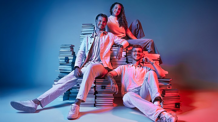 Tre studenter mot blå bakgrund