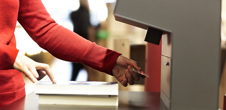 Photo of hand holding book by the self-service-machine