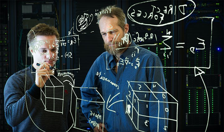 En lärare och en elev ritar matematiska figurer på en svart tavla