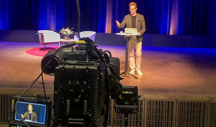 Henrik Andershed på scenen med tv-kameran framför.