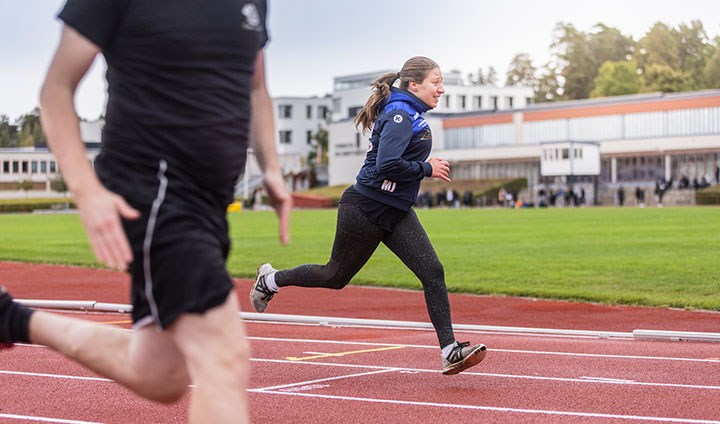 Foto på två personer som springer på en löpbana.