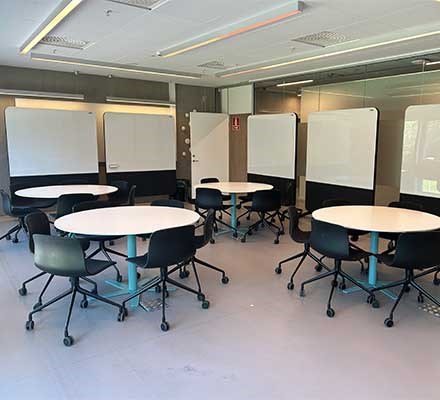Vy 2045 - Runda bord med stolar runt framför rullbara whiteboardtavlor