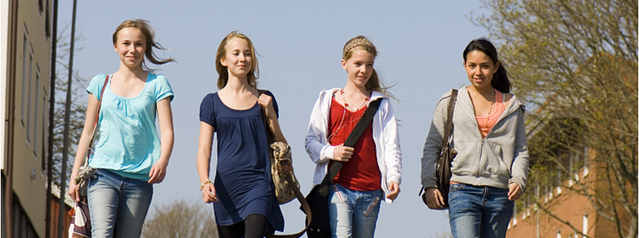 Fyra leende tjejer på promenad  i vårsolen 