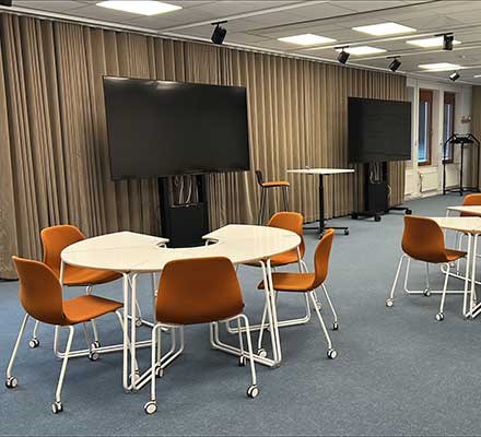 Vy 1 - bord i grupper framför två TV-skärmar
