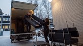 En soffa lastas på en lastbil utanför Örebro universitet. En man och en kvinna i arbetskläder lyfetr upp soffan.