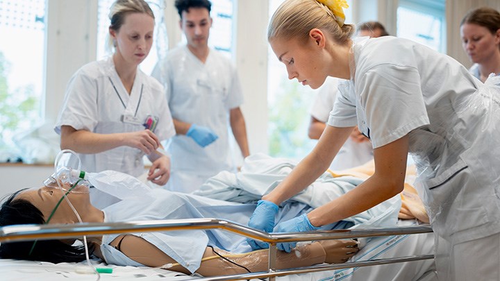 Sjuksköterskestudenter jobbar med en docka i helfigur på kliniskt tränigscenter.