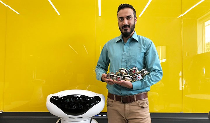  Ali Abdul Khaliq ses tillsammans med en stor och flera små robotar.