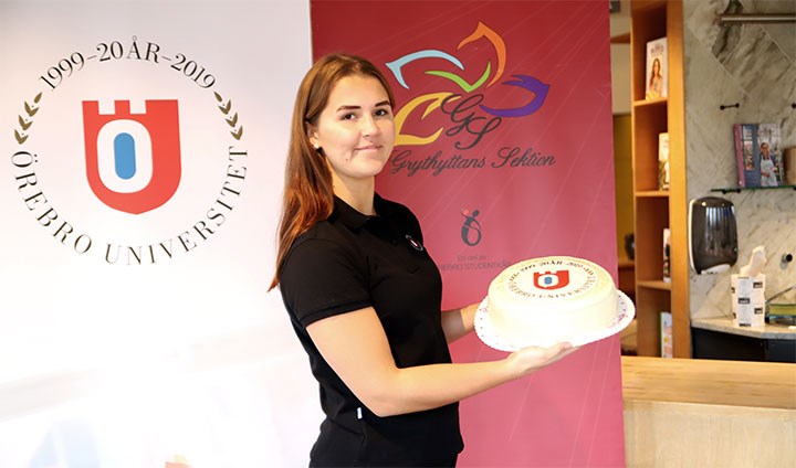Amanda Granell håller i en tårta med Örebro universitets jubileumslogotyp på.