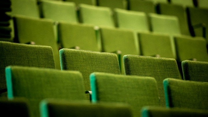 Bild på tomma gröna stolar i en hörsal