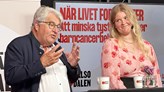 Claes Möller i svart kavaj och vit skjorta samtalar med  Linnea Ruf som har en blommig top. de står vid ett ståbord. . 