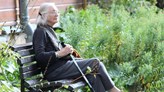 Äldre kvinna sitter på en parkbänk.