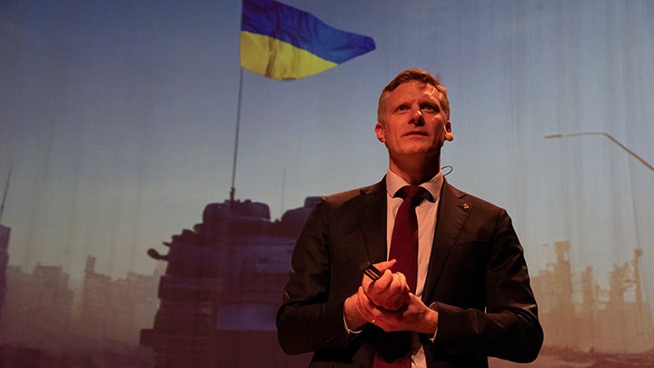Robert Egnell framför en bild på ett stridsfordon med ukrainsk flagga.