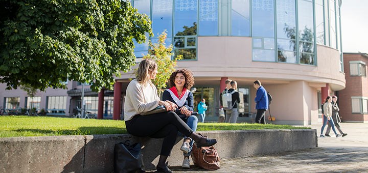 Två studenter sitter utanför universitets biblioteket