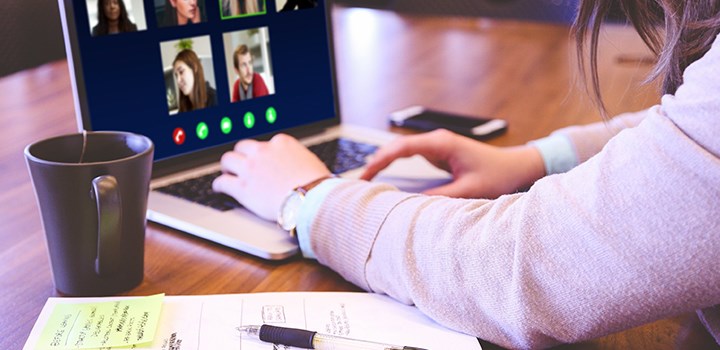 Person sitting in a digital meeting on a laptop.