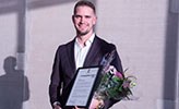 Joakim Petersson håller i ett inramat diplom och en blomsterbukett.