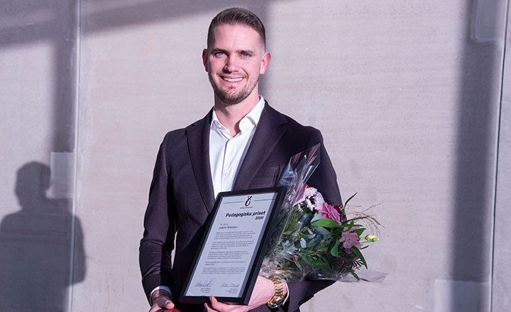 Joakim Petersson håller i ett inramat diplom och en blomsterbukett. 