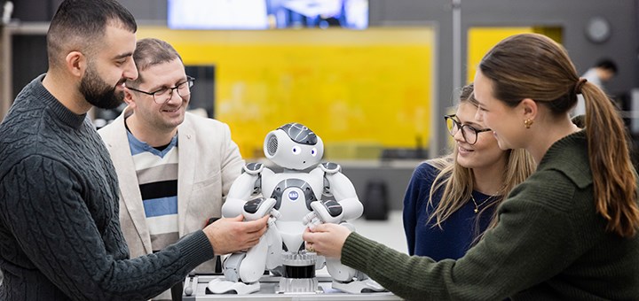 Four people are interacting with a robot standing on a table