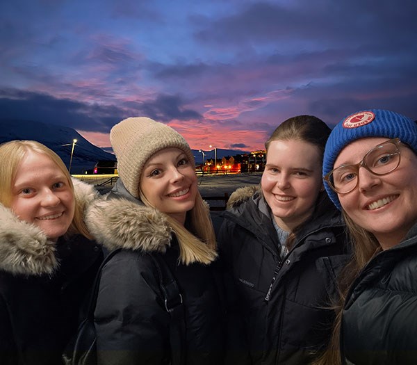 Fyra studenter framför en miljöbild från Svalbard