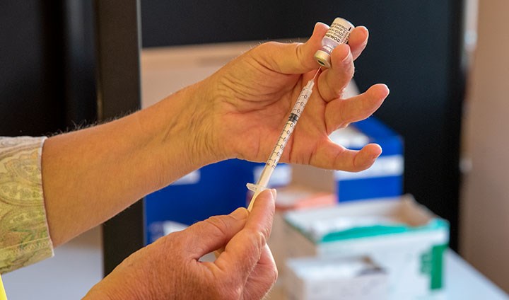 A pair of hands drawing vaccine into a syringe.