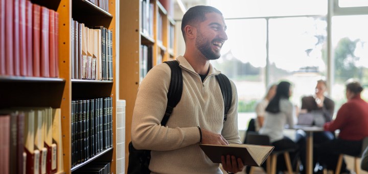 En manlig student står i biblioteket på campus Örebro.