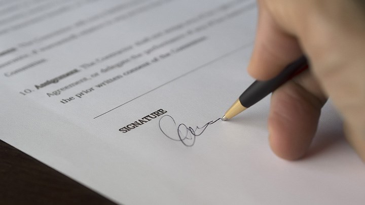 Photo of a hand signing a paper.